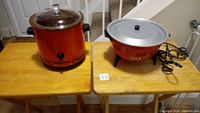 Pair of cooking appliances on wooden table: Rival Crock-Pot slow cooker and Asian hot pot