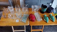 Overview of lot showing assorted clear glassware, Le Creuset cocotte, green ceramic bird figurines, pottery cup, pumpkin container, and clock