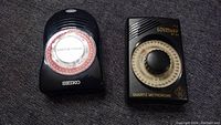 Two quartz metronomes shown from the front: Seiko with rounded dial and Wittner MT 50 with center knob