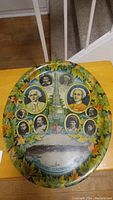 Full image of the oval decorative platter showing colorful maple leaf border and historical portraits with monument in center.