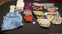 Full lot of reusable diapers, liners, and wet bag laid out on a surface showing quantity and variety.