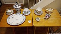 Photo showing two tea cup and saucer sets from England and one from Japan, bone china flower decor in wheelbarrow design, bone china sugar bowl, and small ceramic container from Japan.
