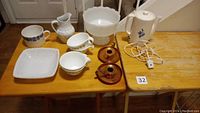 Overhead photo showing all items on wooden table including tea pot, pitcher, bowls, cups, and candle holders
