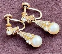 Close-up photo of the pair of vintage 14K gold screw-back earrings with pearl drops displayed on a dark background showing the details of the pearls and gold decorative elements.