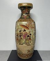 Front view of a large vintage Satsuma floor vase with detailed scenes of Geisha women under an umbrella and floral backgrounds, gold accents visible.