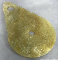 Front view of Chinese jade pendant showing circular hole in center and carved designs