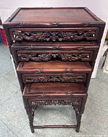 Front view of four nested rosewood tables stacked