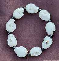 Top view of the full bracelet laid flat showing white skull shaped beads alternating with smaller black beads connected by elastic.