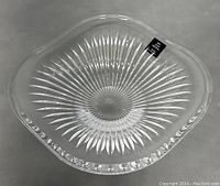 Clear Rogaska crystal bowl showing starburst cut pattern at the base and smooth rim with subtle engraved floral pattern, no chips or cracks visible.