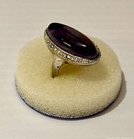 Oval cabochon amethyst ring set in 925 sterling silver on cream foam display showing ring size and setting detail