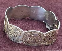 Top view of vintage sterling silver bangle showing engraved floral and leaf patterns and scalloped design.