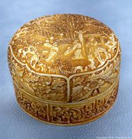 Top and side view of round vintage Chinese carved lacquer box showing detailed carved scenes of figures and floral motifs.
