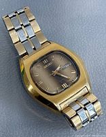 Front view of vintage Seiko wrist watch showing gold-tone case, brown gradient dial, gold hour markers, and metal bracelet.