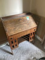 Front view of antique wooden secretary desk with closed drop-front and drawer visible.