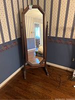 Front view of the tall standing mirror against wall, showing full wooden frame and clear reflective surface.