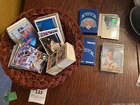Basket with assorted baseball cards, Beckett card holder boxes, small sport card binder, and other card packs.
