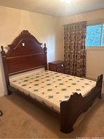 Full view of the double wooden bed with mattress, showing headboard and side table in the room