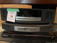 Stacked units: Bose Wave Music System on top, Bose 3-disc CD changer in middle, Samsung Blu-ray player on bottom