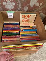 Box of assorted children's and YA books, showing 'Hop on Pop' prominently