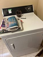 Full view of dryer showing top surface with items and front-load door