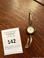 Full watch view showing round face with Gucci logo dial, green and red bezel, slim gold tone metal bracelet and safety chain.