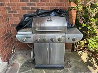 Full view of the Master Chef stainless steel BBQ grill with closed lid, multiple burner control knobs, cabinet base and side shelves, situated outdoors.