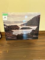 Front view of metal wall art featuring ocean and rocky coastline under cloudy sky