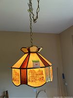 Full view of the hanging light fixture showing the stained glass panels and suspension chain.