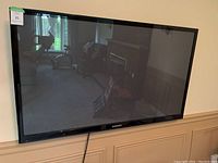 Front view of the Samsung 54-inch flat screen TV mounted on the wall showing the screen and brand logo.