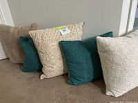 Side view of six assorted accent pillows in beige, teal, cream colors, showing textures and variety.