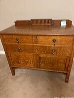 Front view of antique wooden chest showing two drawers on top and cabinet doors below, with carvings and metal keyhole handles.