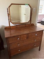 Front view of oak dresser with attached octagonal mirror showing three drawers and glass knobs.