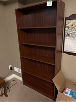 Front and side view of the tall wooden bookcase showing multiple adjustable shelves.