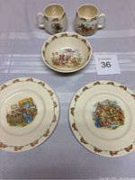 Full view of set including two mugs, one bowl, two plates arranged and numbered on light fabric background