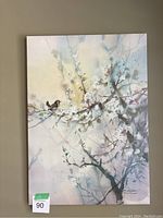 Full view of the canvas painting showing branches with blossoms and a bird, mounted on a wall.