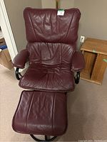 Front view of burgundy leather swivel recliner and matching ottoman