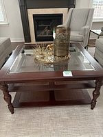 Full view of two-tiered coffee table with glass inset and dark wood frame