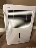 Front view showing intake grille, water tank window, Midea logo and “70 pints” printing