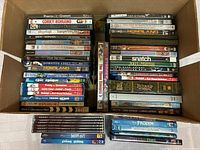 Top view of a box containing a variety of DVDs arranged in three stacks showing titles and cover art.