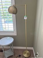 Full view of gold floor lamp showing its design and size relative to nearby furniture.