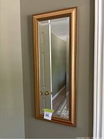 Full view of the gold framed rectangular mirror hanging on wall showing overall shape and size.