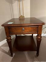 Full view of wooden side table showing drawer and lower shelf with turned legs