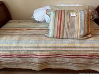 Twin bed made up with a striped comforter and matching pillow case on a wooden bed frame