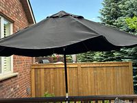 Large black outdoor umbrella open, showing full canopy and outdoor setting.