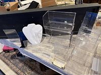 Photo showing varied acrylic retail display stands and holders arranged together on a table.