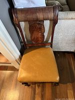 Front view of wooden slipper chair showing carved back and leather seat.
