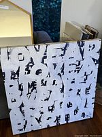 Photo of 3.5x3.5 ft oil painting featuring large overlapping block letters spelling LOVE, FEAR, and EARTH in white on dark background.