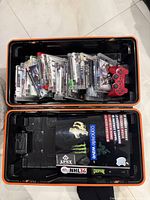 Open hard case showing inside top and bottom compartments with numerous PS3 game cases and discs, red controller, and PS3 console with stickers inside hard plastic Call of Duty themed case.