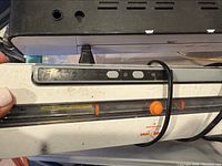 Photo showing white vacuum sealer control panel with buttons including an orange slider and vacuum seal button with cord wrapped.