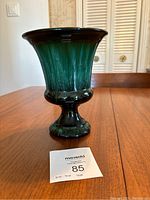 Front view of small Blue Mountain Pottery vase showing green to black glaze, pedestal base and flared rim.